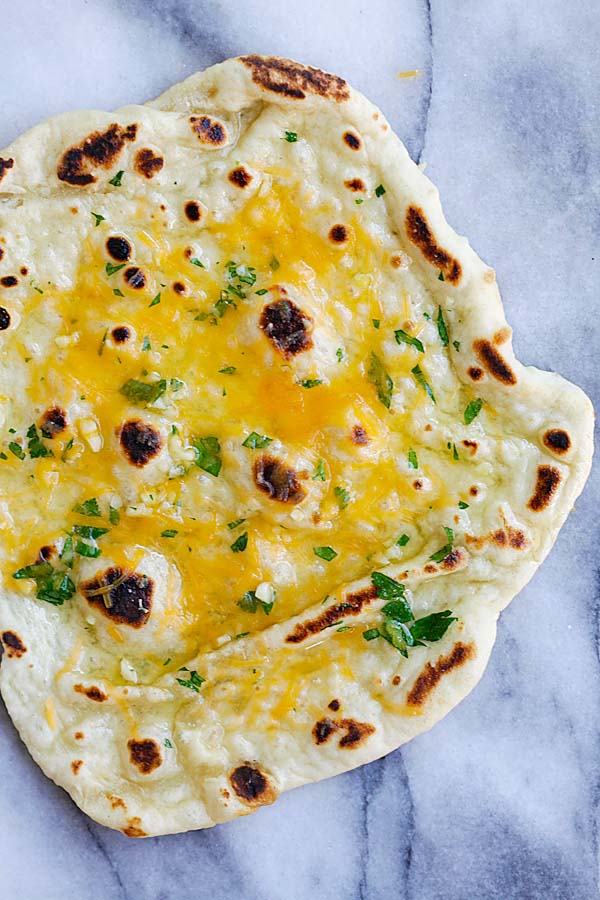 Easy and healthy homemade Indian cheese naan topped with garlic butter and cheddar cheese, ready to serve.