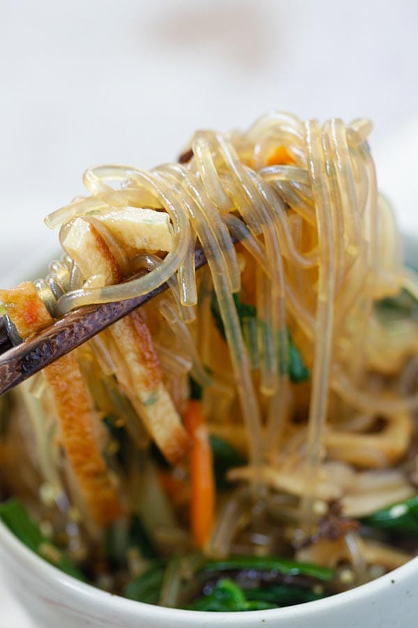Japchae Korean noodle picked with a pair of chopsticks.