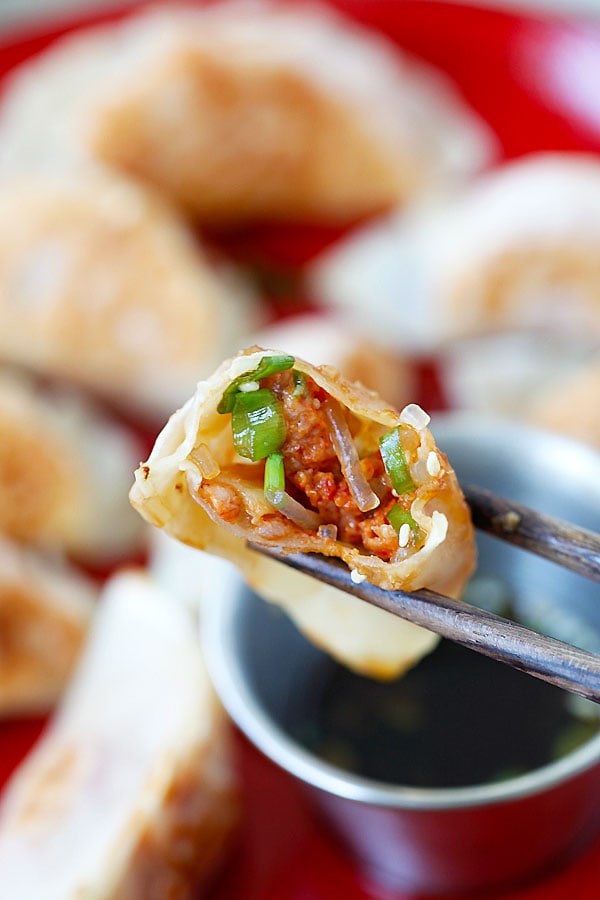 Juicy and delicious interior of Kimchi Dumplings picked with a pair of chopsticks.