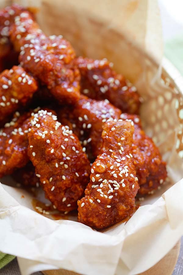 Crispy and juicy red Korean Fried Chicken in serving basket topped with sesame seeds.