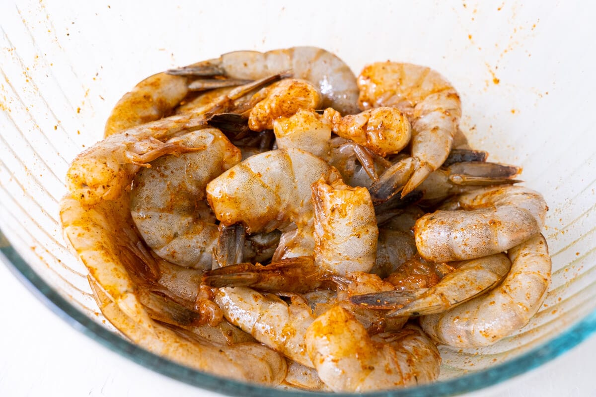 Shrimp tossed with olive oil and Old Bay seasoning in a bowl. 