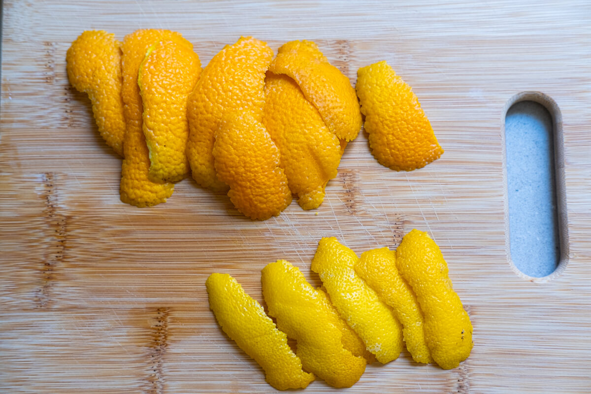 Thick slices of orange and lemon rind arranged on a chopping board. 