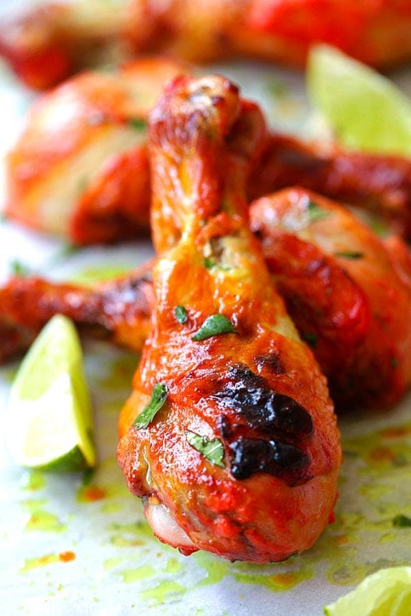 Tandoori chicken baked in the oven an served with lime wedges and cilantro.